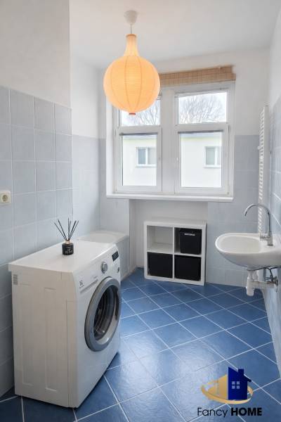 Bathroom in a 2-room apartment with a washing machine, sink, and blue tiles.