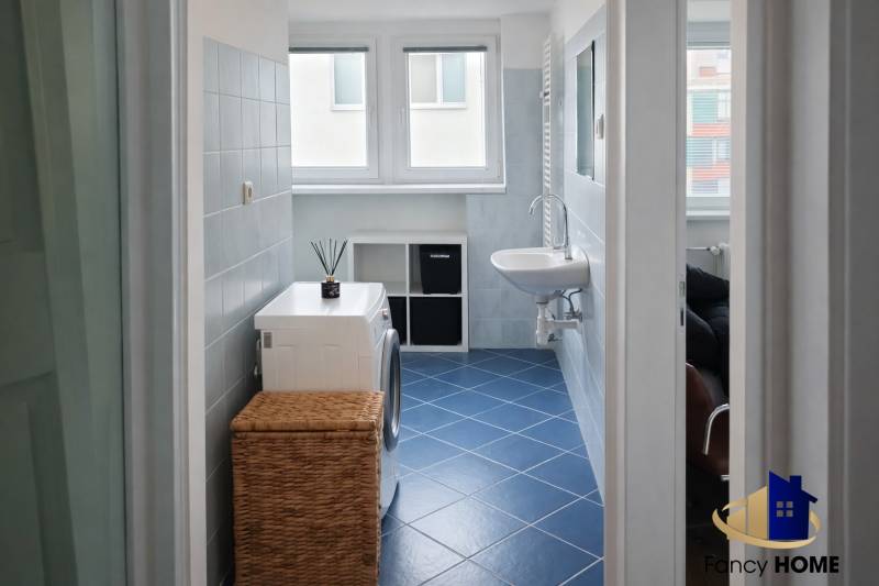 Washing machine with a basket and a sink in a 2-room apartment with blue tiles.