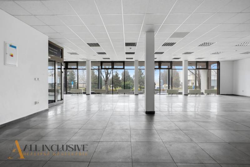 Spacious commercial spaces with large windows, light tiles, and columns.