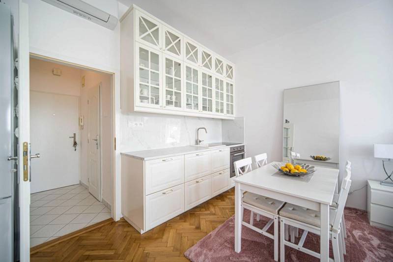 A kitchen in a one-room apartment with a wooden decor floor and a dining table.
