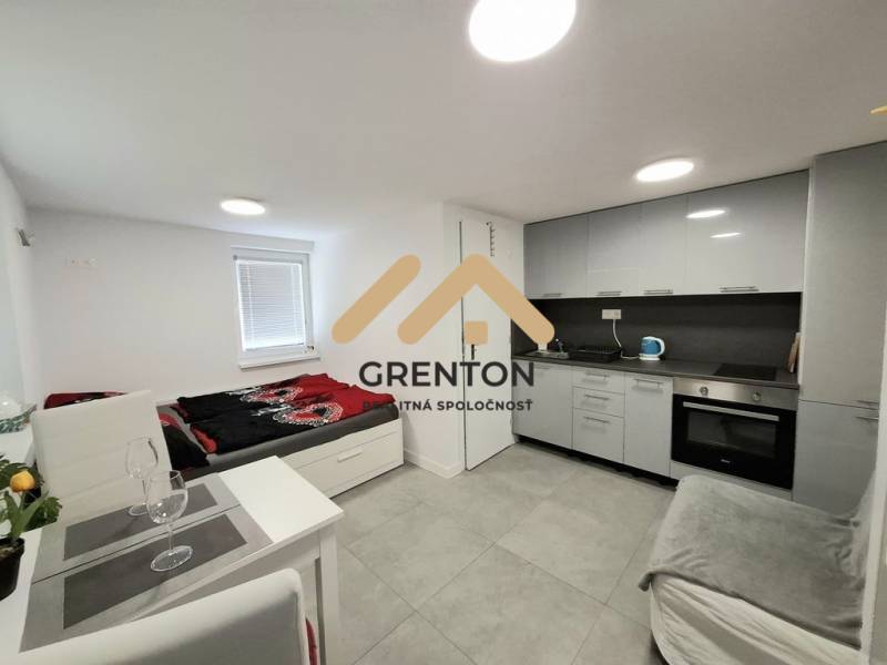 A kitchenette and a bed in a cabin with gray cladding and furnishings.