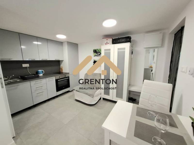 A kitchen in a cottage, with a dining table and gray kitchen cabinets.