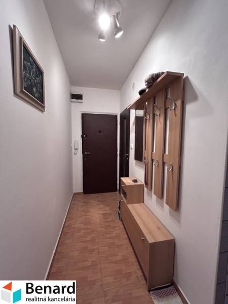 A hallway with a coat rack wall and a wooden decor floor in a 2-room apartment.