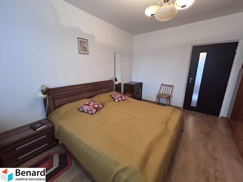 Bedroom in a 2-room apartment with wood-patterned flooring, a double bed, and furniture.