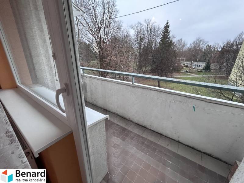Balcony of a 2-room apartment with a view of the surroundings, tiles, trees.