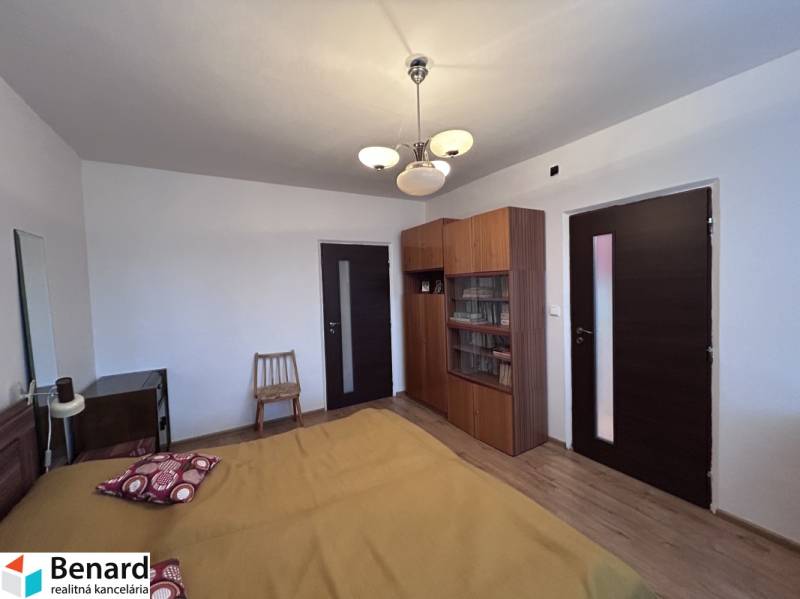 Bedroom in a 2-room apartment with a bed, wardrobe, and floor with wooden decor.