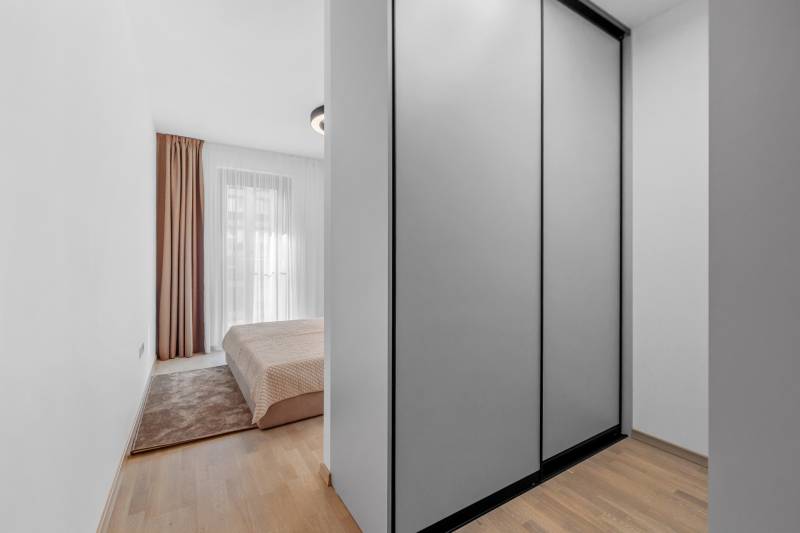 Bedroom in a 2-room apartment with a built-in wardrobe and a floor with a wooden decor.