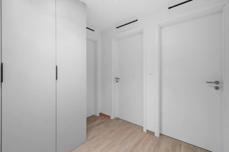 A hallway in a 2-room apartment with a built-in wardrobe and a floor with a wooden decor.