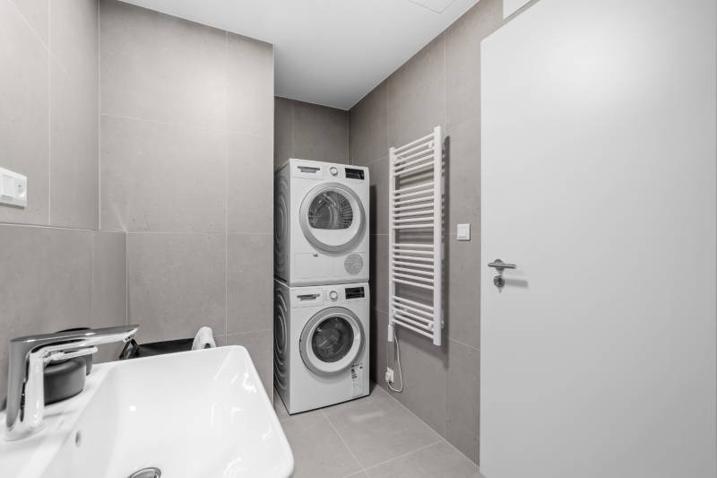 Bathroom in a 2-room apartment with a sink, washing machine, and dryer, tiled walls.