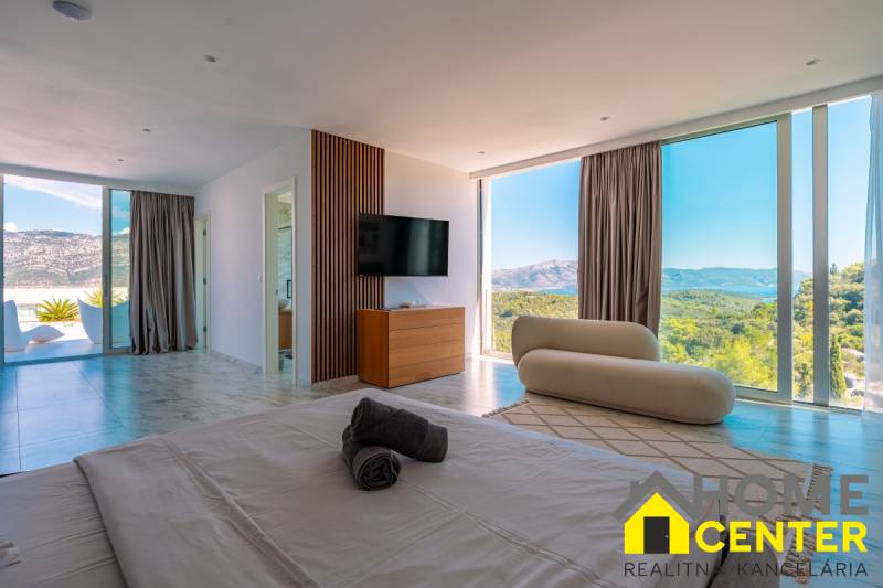 Bright bedroom in a villa with a view through large windows, wooden decor flooring.