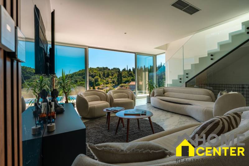 Living room of the villa with large windows, comfortable seating, and a view of nature.