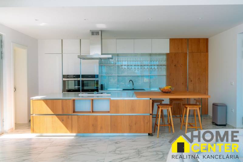 A kitchen in a villa with a wood-patterned floor, an island, and bar stools.
