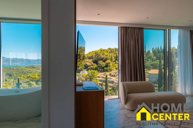 Interior of a villa with a view of nature, bathtub by the window, comfortable armchair.