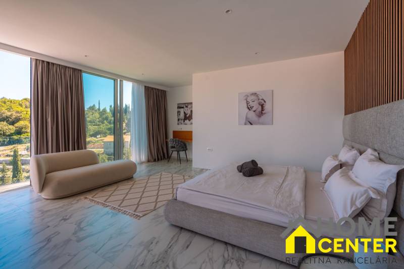 A bedroom in a villa with large windows and marble flooring, featuring stylish furniture.