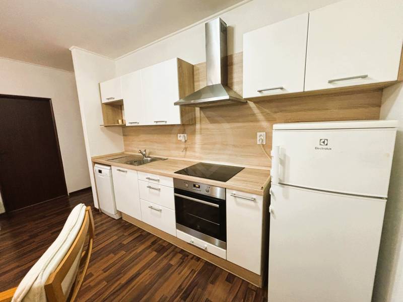 A kitchen in a 2-room apartment with a wood-patterned floor and white appliances.
