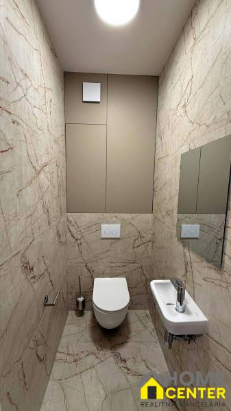 A toilet with marble tiles in a 2-room apartment.