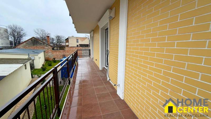 A balcony in a 3-room apartment in Komárno with a view of the courtyard and a brick facade.