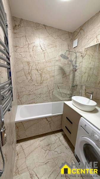 Bathroom with a bathtub, sink, and washing machine in a 2-room apartment. Tiles with a marble appearance.