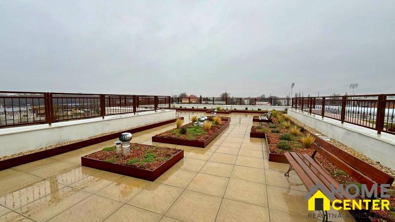 Rooftop terrace of a 3-room apartment in Komárno with benches and greenery.