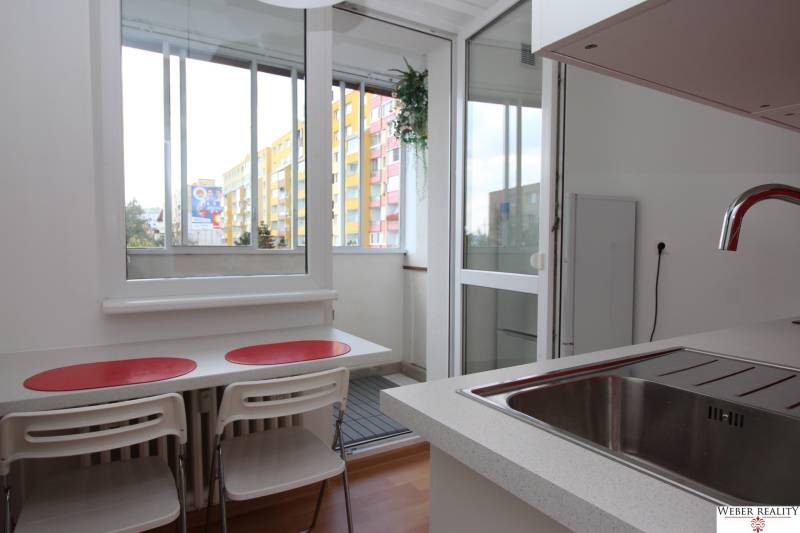 Kitchen in a studio apartment with a view and a balcony, floor with wood decor.