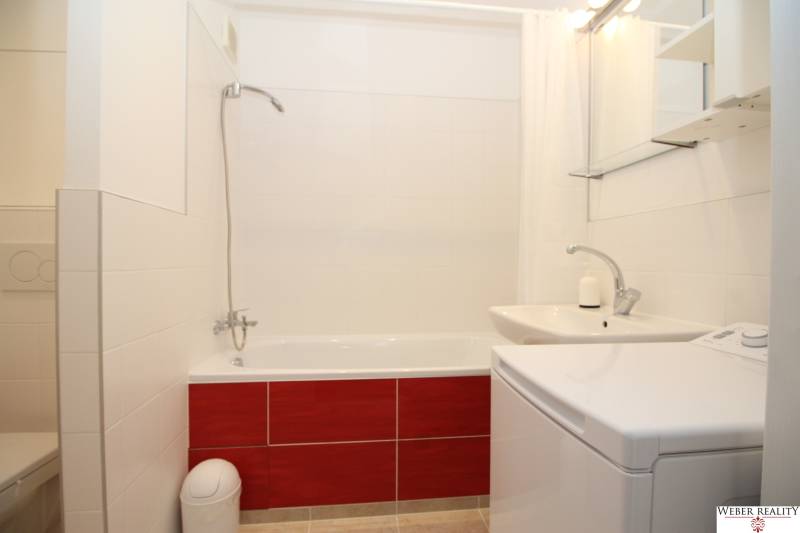 Bathroom with a bathtub, sink, and washing machine in a studio apartment.