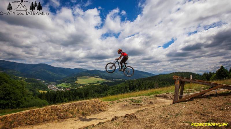 A cyclist is jumping on a mountain bike over the landscape in the recreational grounds near Mýto pod Ďumbierom.