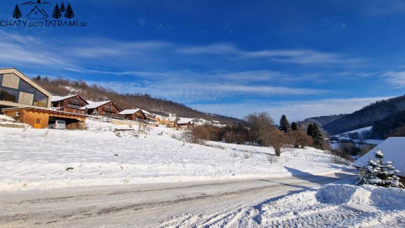 A snowy landscape with wooden cottages on recreational grounds near Fongrub Street in Mýto pod Ďumbierom.