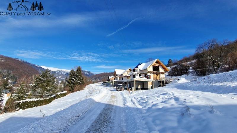 A snowy landscape and houses under construction on plots in Mýto pod Ďumbierom.