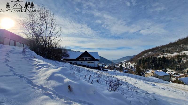 Snow-covered residential lands in Mýto pod Ďumbierom, surrounded by hills and forests.