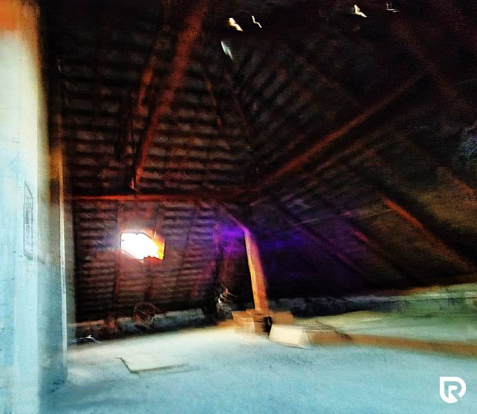 Attic in a family house with wooden beams and a window.