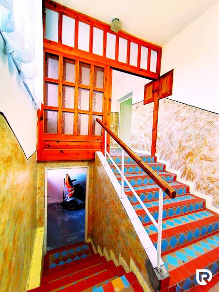 A colorful staircase leads to the upper floor of the family house, adorned with a wooden railing.