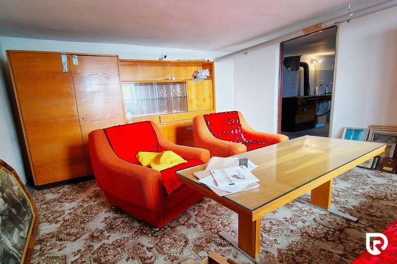 Living room in a family house with older armchairs, a table, and a glass cabinet.