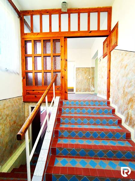 A staircase in a family house with colorful tiles and a wooden railing.