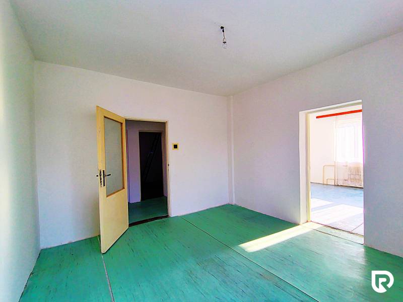 The interior of a family house with open doors, white walls, and a green floor.