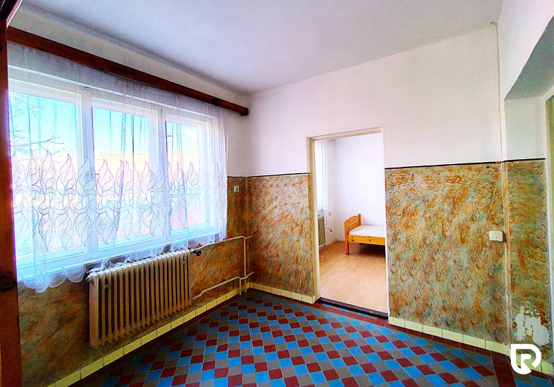 Interior of a family house with tiles, a radiator, and a window with a curtain.