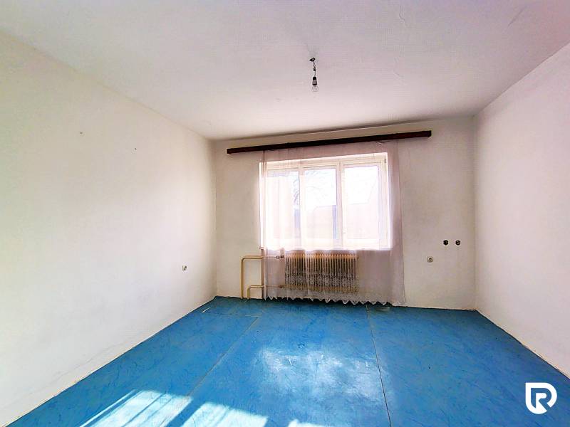 An empty room with white walls and a blue floor in a family house.