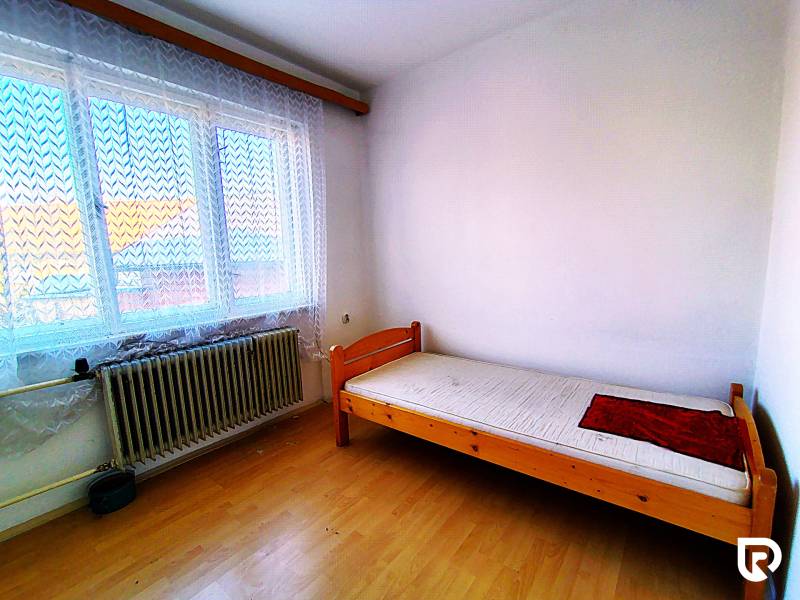 Single room with a bed and a window, wooden decor flooring, in a family house.