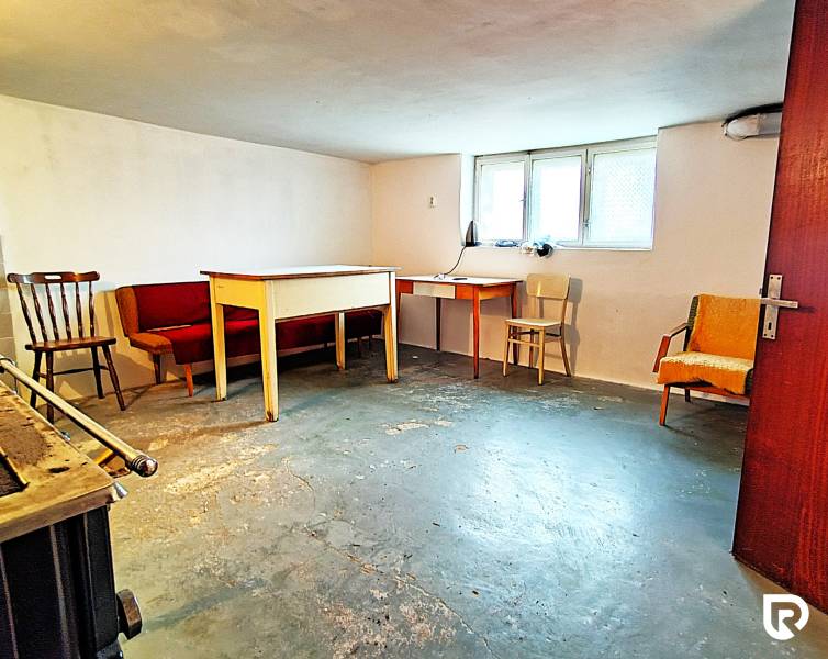 Basement in a family house with furniture and a window, concrete floor.