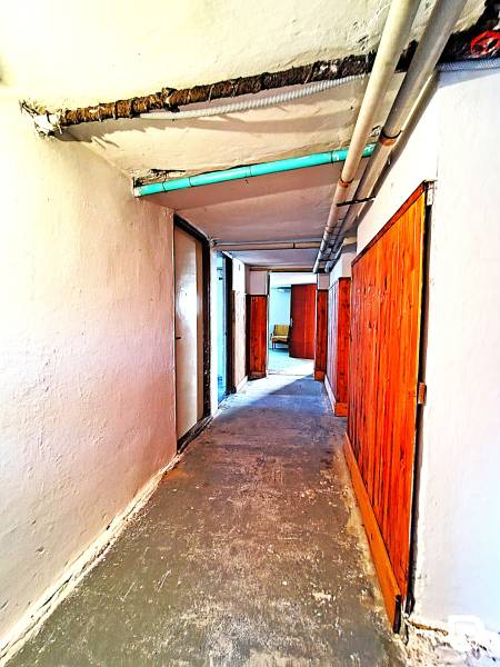 A hallway of a family house with wooden doors and exposed pipes.