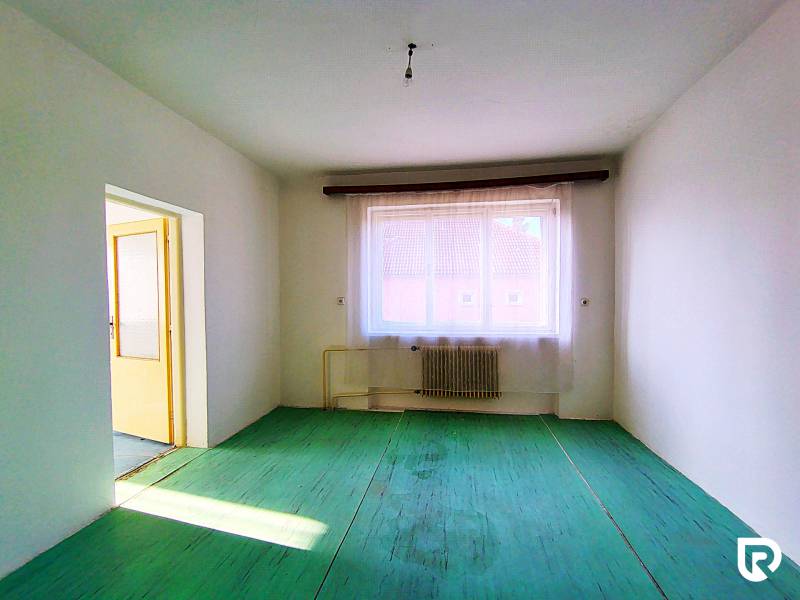 A room in a family house with a radiator, green floor, view of the rooftops.