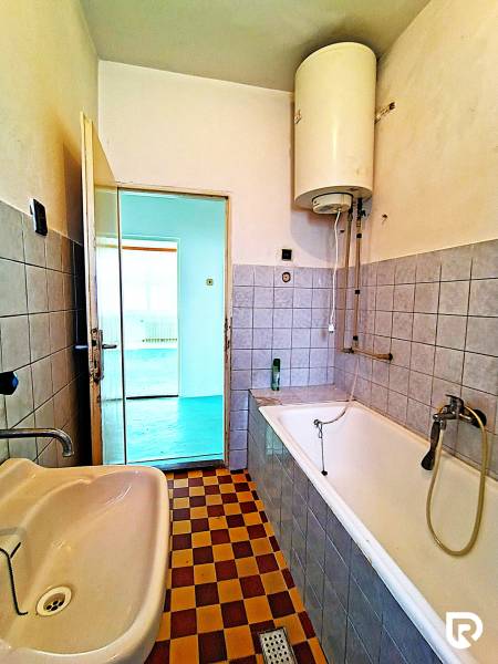 A bathroom in a family house with a bathtub, a sink, and a checkered tile floor.