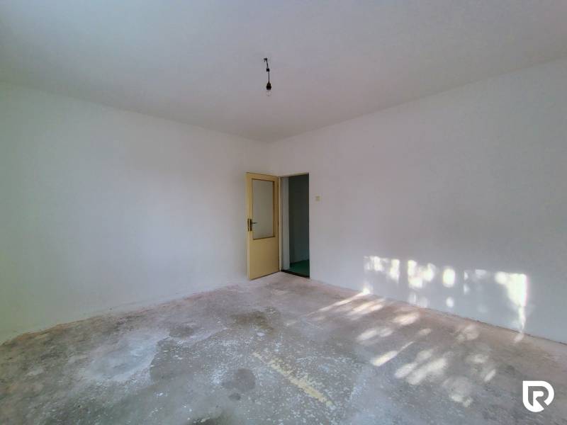 Empty room with white walls and a concrete floor in a family house.