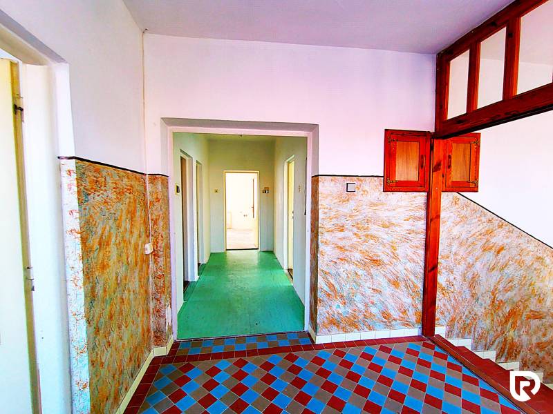 A hallway in a family house with colorful tiles and wooden wall paneling.