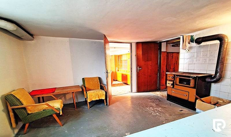 A room in a family house with armchairs, a table, and an old stove.