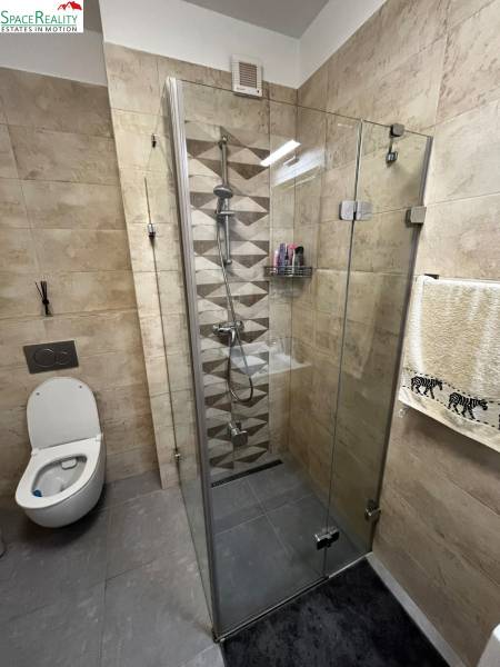 Bathroom in a 2-room apartment with a glass-enclosed shower and toilet, tiled.