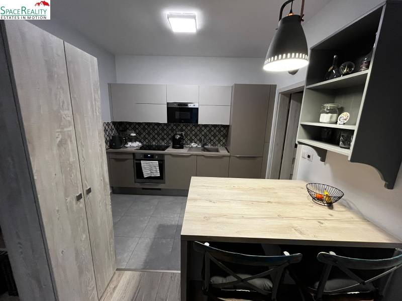 A kitchen in a 2-room apartment with tiles, a wooden decor floor, and dark gray cabinets.