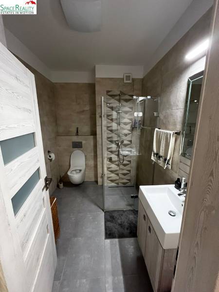 A bathroom with a modern shower enclosure and designer tiles in a 2-room apartment.