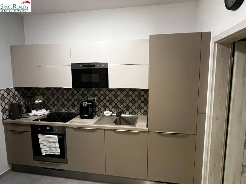 A kitchen in a 2-room apartment with modern appliances and patterned tiles.
