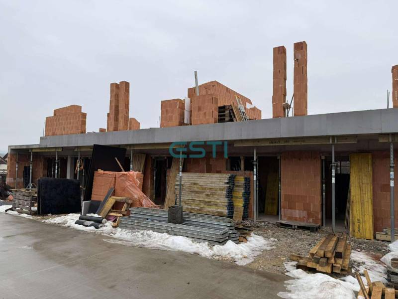 Construction of a family house in Višňové, Višňové, made of red brick, with piles of wood.