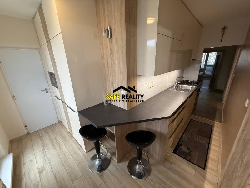 A kitchen in a 3-room apartment with a wooden decor floor and a dining counter.